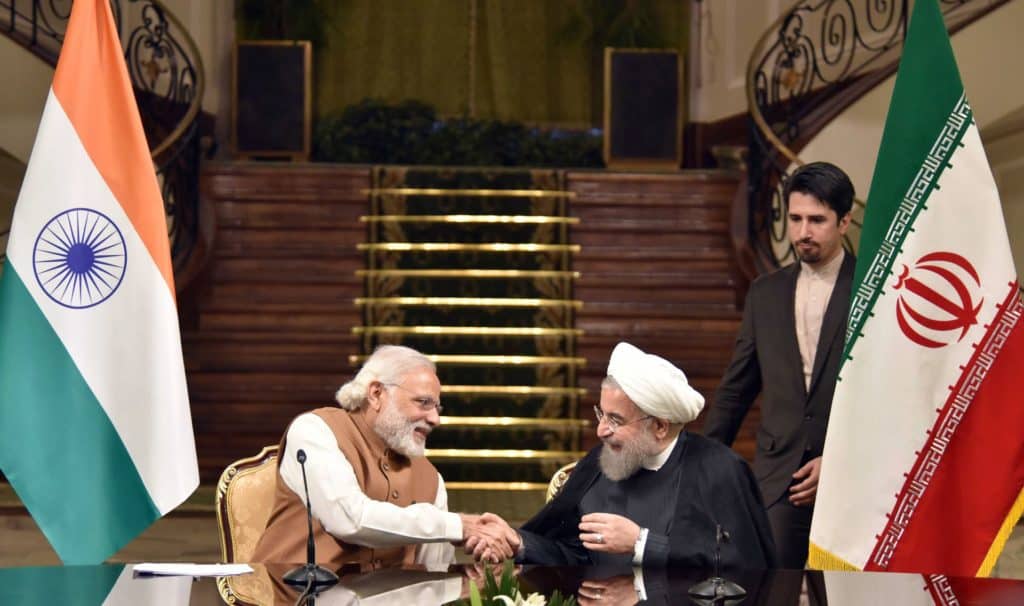 Indian and Iranian leaders shaking hands during business meeting.