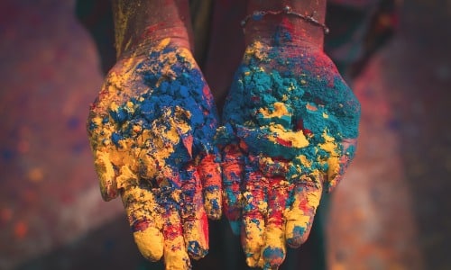 Vibrant Holi powder on hands symbolizing celebration and new beginnings in Indian business setup pro.